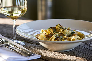 Pappardelle pasta with creamy mushroom sauce and white wine glass on a rustic w, a Photo by Studio ANNA