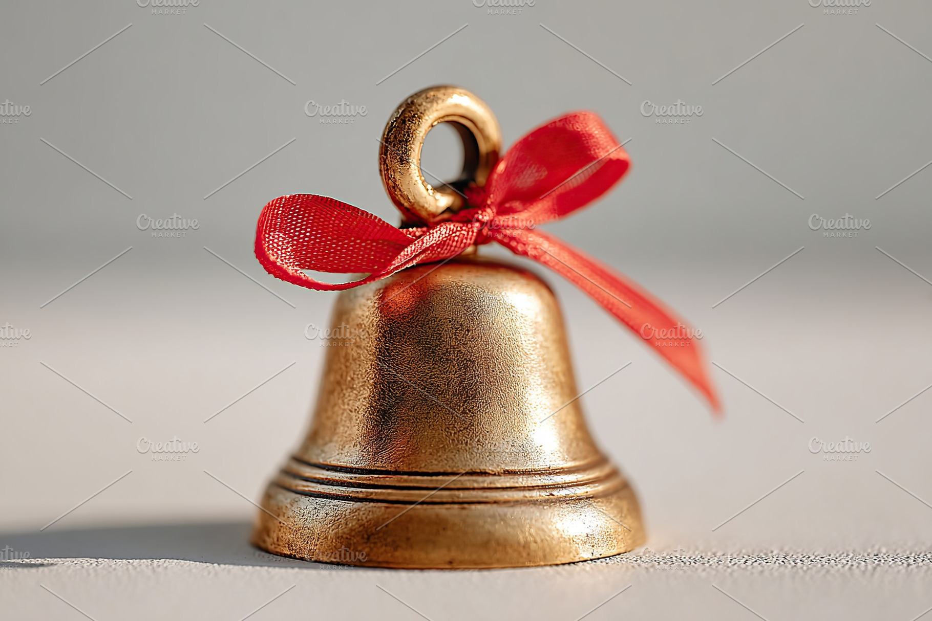 Golden bell with red ribbon on a neutral background showcasing festive charm an, a Photo by AlyaAnd