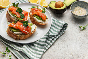 Preparing avocado salmon toasts with sesame seeds and lemon, a Food & Drink Photo by Olena Rudo