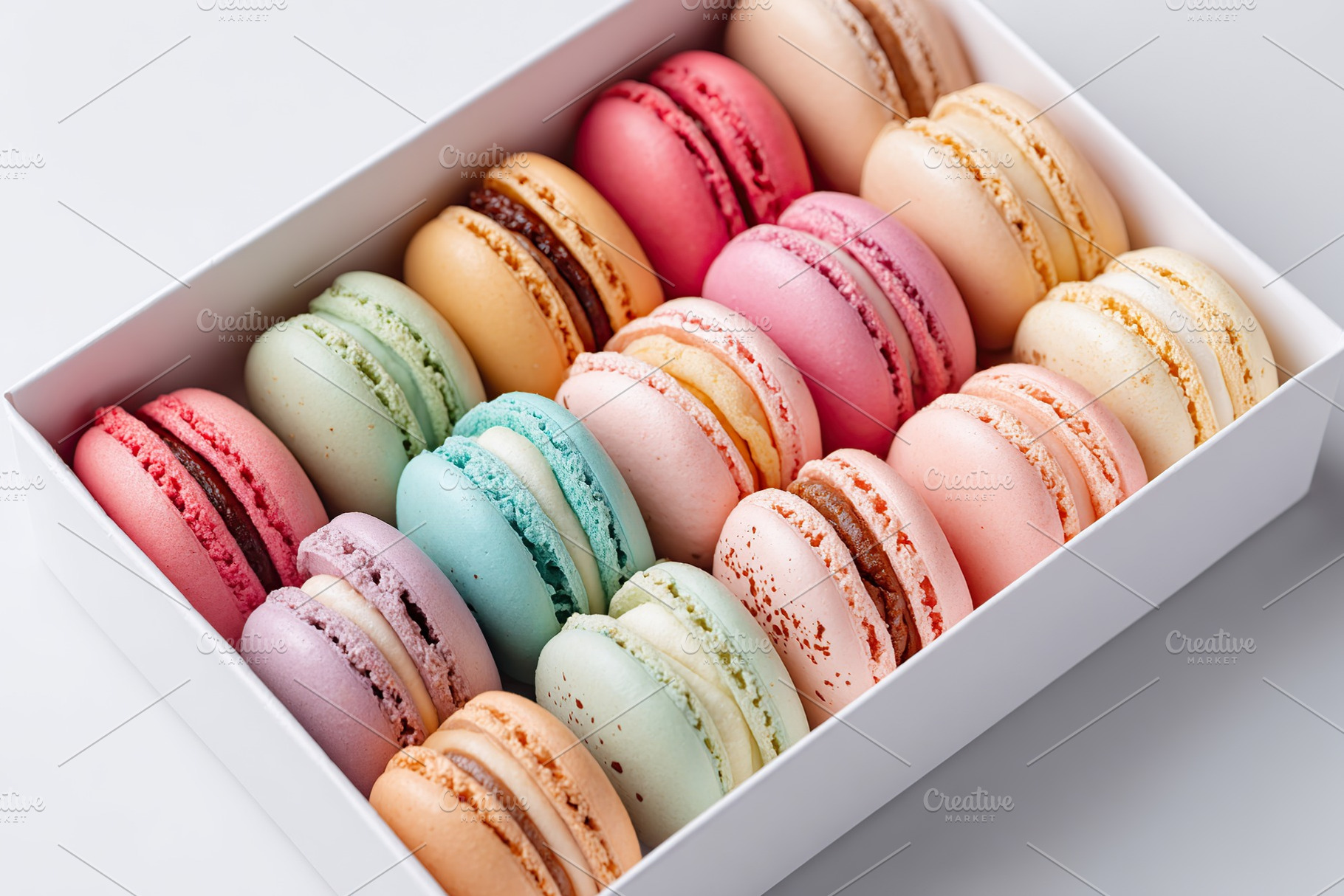 Assorted pastel macarons displayed in a decorative box for a delightful treat, a Food & Drink Photo by AlyaAnd