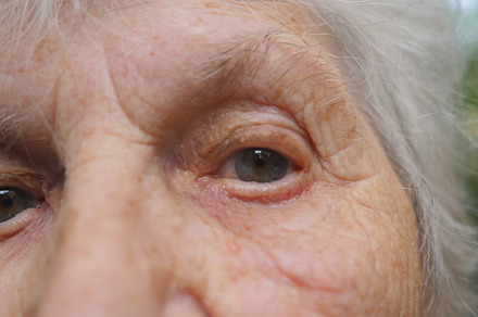 Close up portrait of old woman watching into camera and then looking up. Eyes of an elderly lady with wrinkles around them. Slow motion