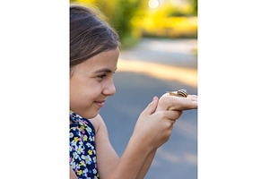 A child is studying a snail in the, a Nature Photo by yanadjana