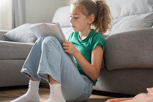 Schoolgirl Sitting on Floor at Home Reading and Writing in Notebook, a Person Photo by etorres69
