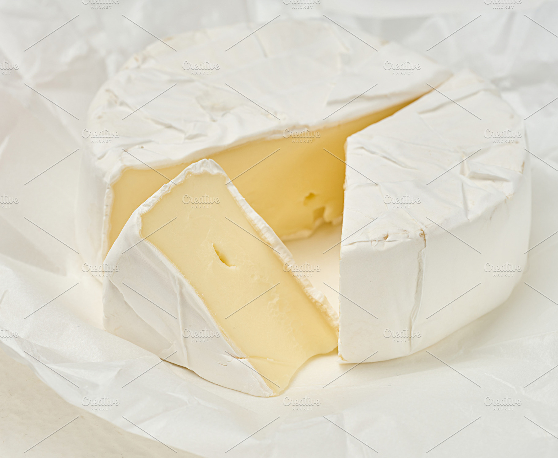 A round head of soft Camembert cheese with white mold, one trian, a Food & Drink Photo by ndanko