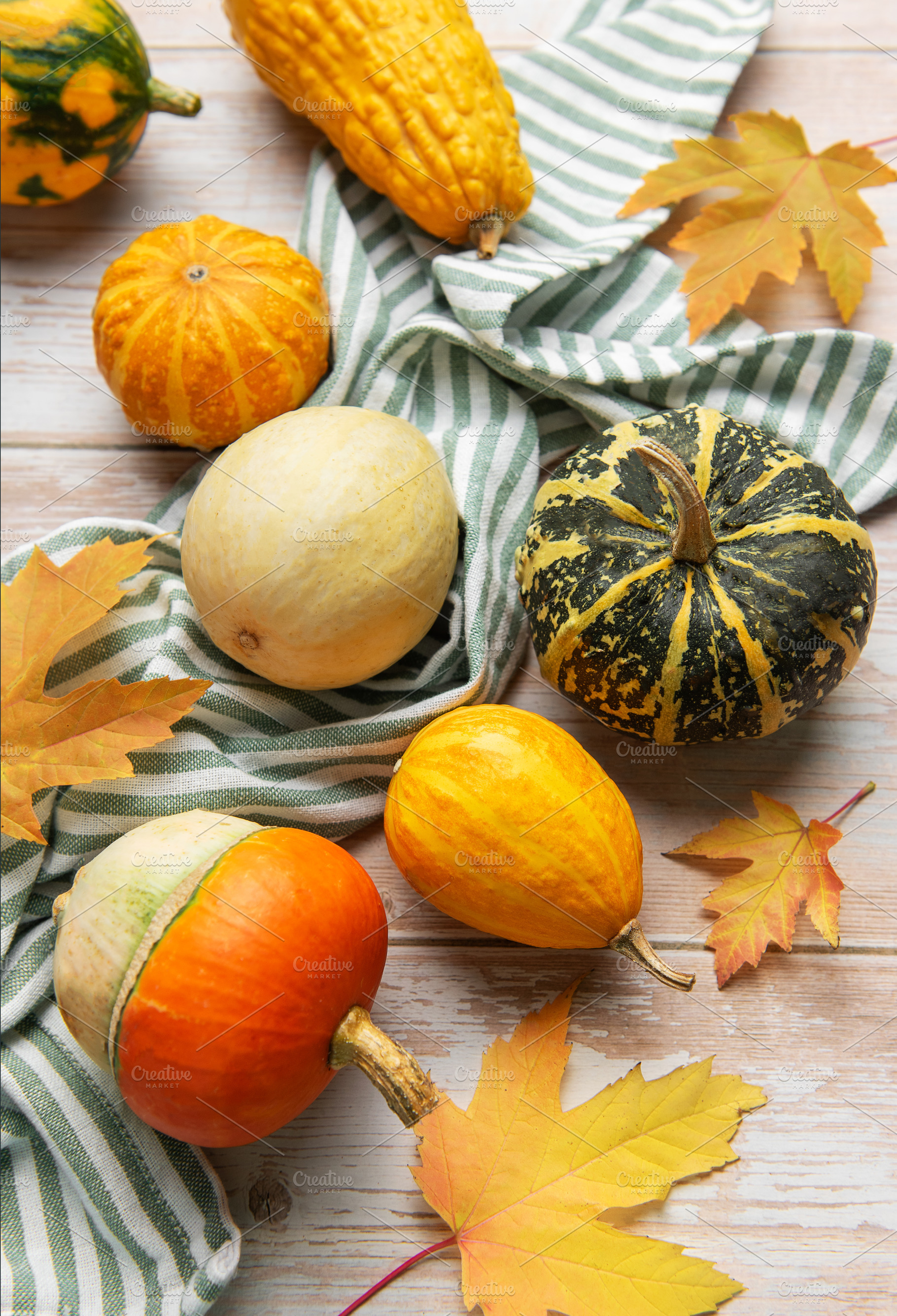 Autumn gourds pumpkins and fall leaves on wooden background, a Food & Drink Photo by Olena Rudo