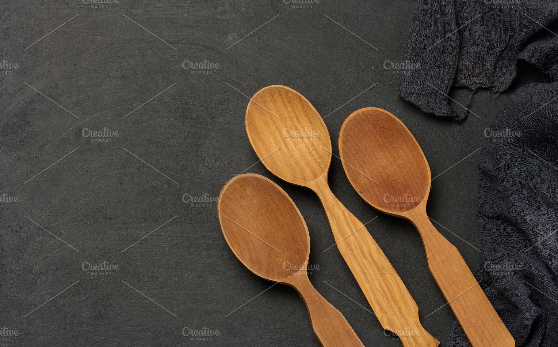 Empty wooden spoons on a dark board with a cloth napkin, top vie, a Food & Drink Photo by ndanko
