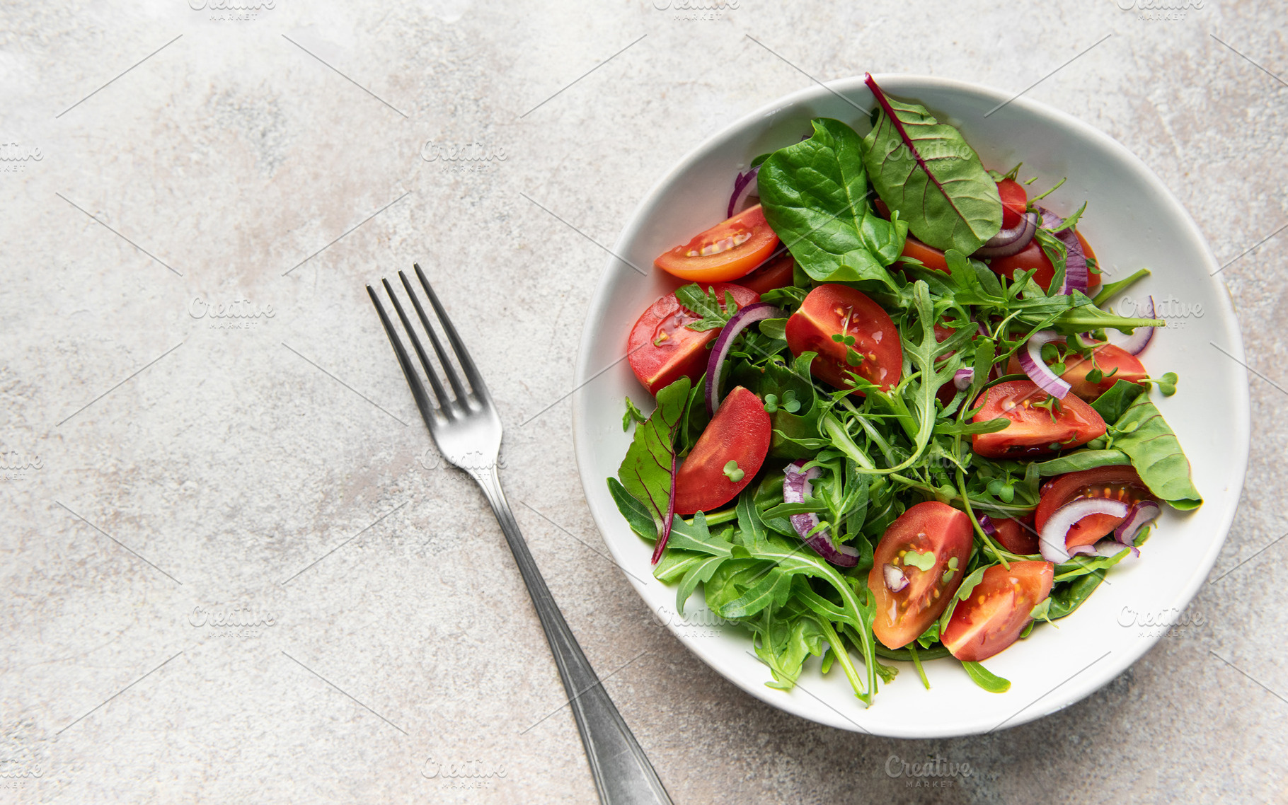 Fresh green salad with tomatoes and red onion, a Food & Drink Photo by Olena Rudo