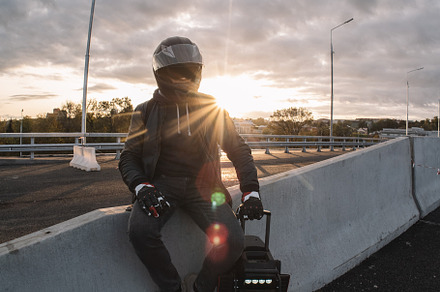 A male rider in protective gear riding an electric wheel. Urban