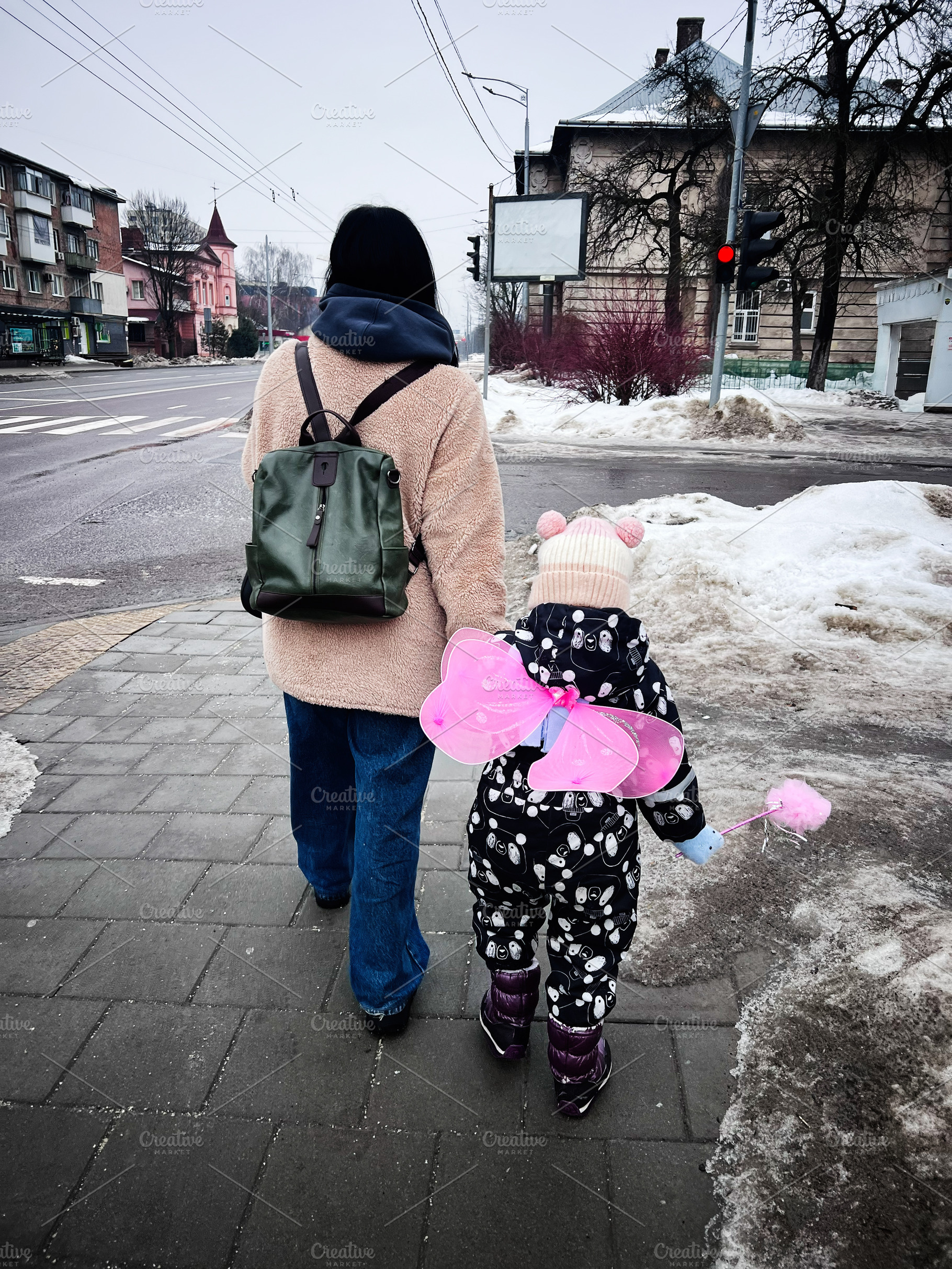 Mother and child walking on a snowy city street in winter, child with pink butt, a Photo by AS photostudio