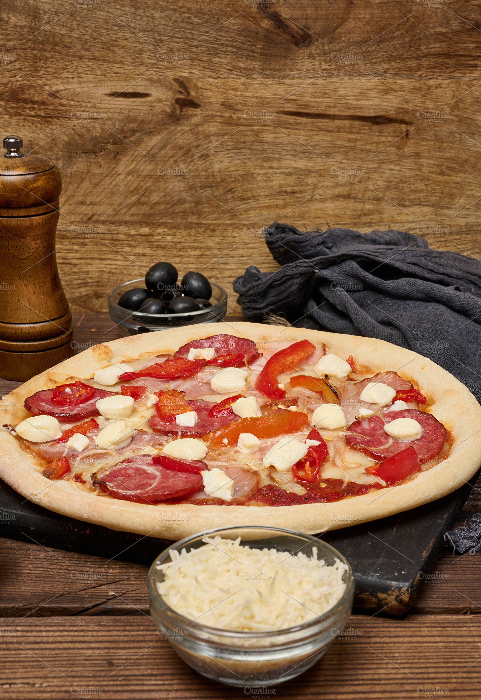 Pizza with salami, ham and mozzarella cheese on parchment, a Food & Drink Photo by ndanko
