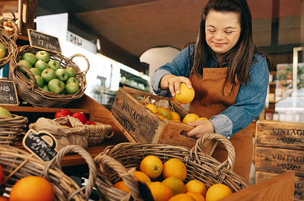 Woman with Down syndrome restocking fresh fruits in a shop, a Person Photo by Jacob Lund