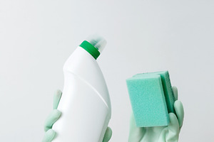 Woman wearing green rubber gloves holding cleaning detergent and sponge, ready, a Photo by matucha