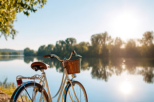 Parked bicycle by a tranquil lake under the clear blue sky at golden hour, a Transportation Photo by AlyaAnd