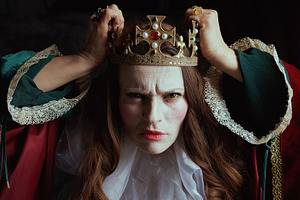 scary medieval queen in red dress with white collar and crown, a Person Photo by Alliance Images