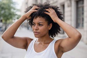 Woman adjusting curly hair outside o, a Photo by Dvoevnore photos