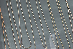 Various gold chains neatly displayed on a jewelry store showcase surface., a Photo by AS photostudio