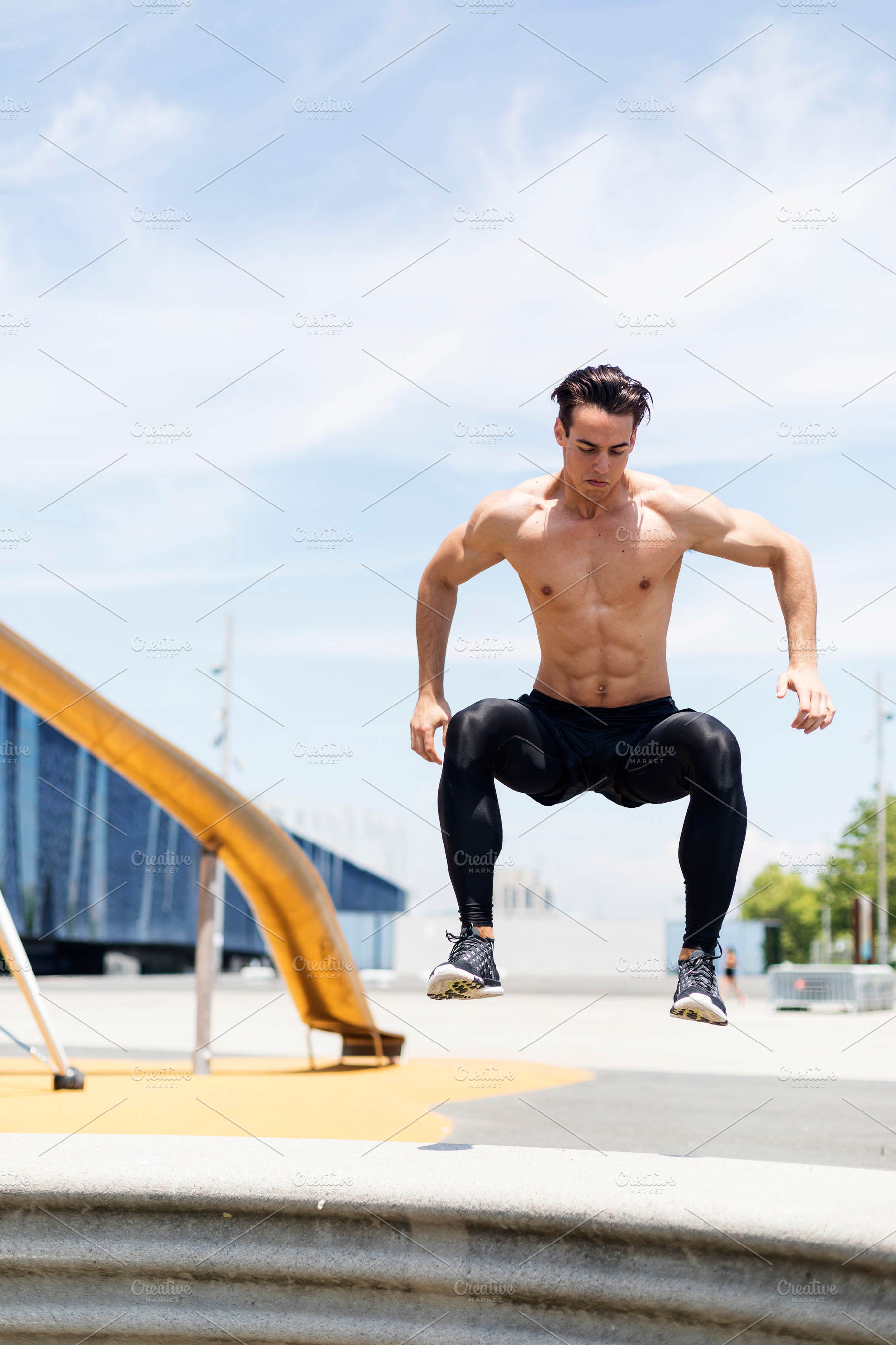 Shirtless athletic man jumping outdoors in city park, a Person Photo by RF Images