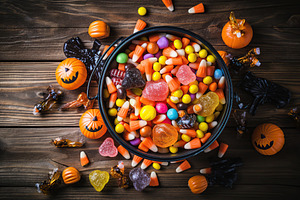 Halloween candies in bucket on brown wooden background, a Holiday Photo by AlyaAnd