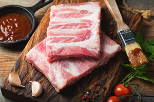 Raw pork ribs with spices, salt and rosemary on dark wooden background, a Food & Drink Photo by Budarinphoto