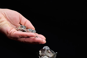 A woman's hand pouring metal coins into a glass jar standing on, a Business Photo by ndanko