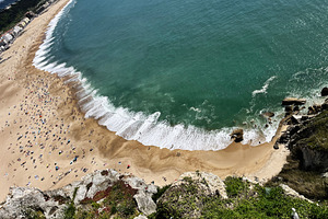 Aerial view of Nazare beach in Portugal with turquoise waves and golden sands, a Photo by AS photostudio