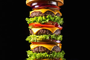 Giant hamburger with melted cheddar cheese overflowing layers, a Food & Drink Photo by GoodGoods