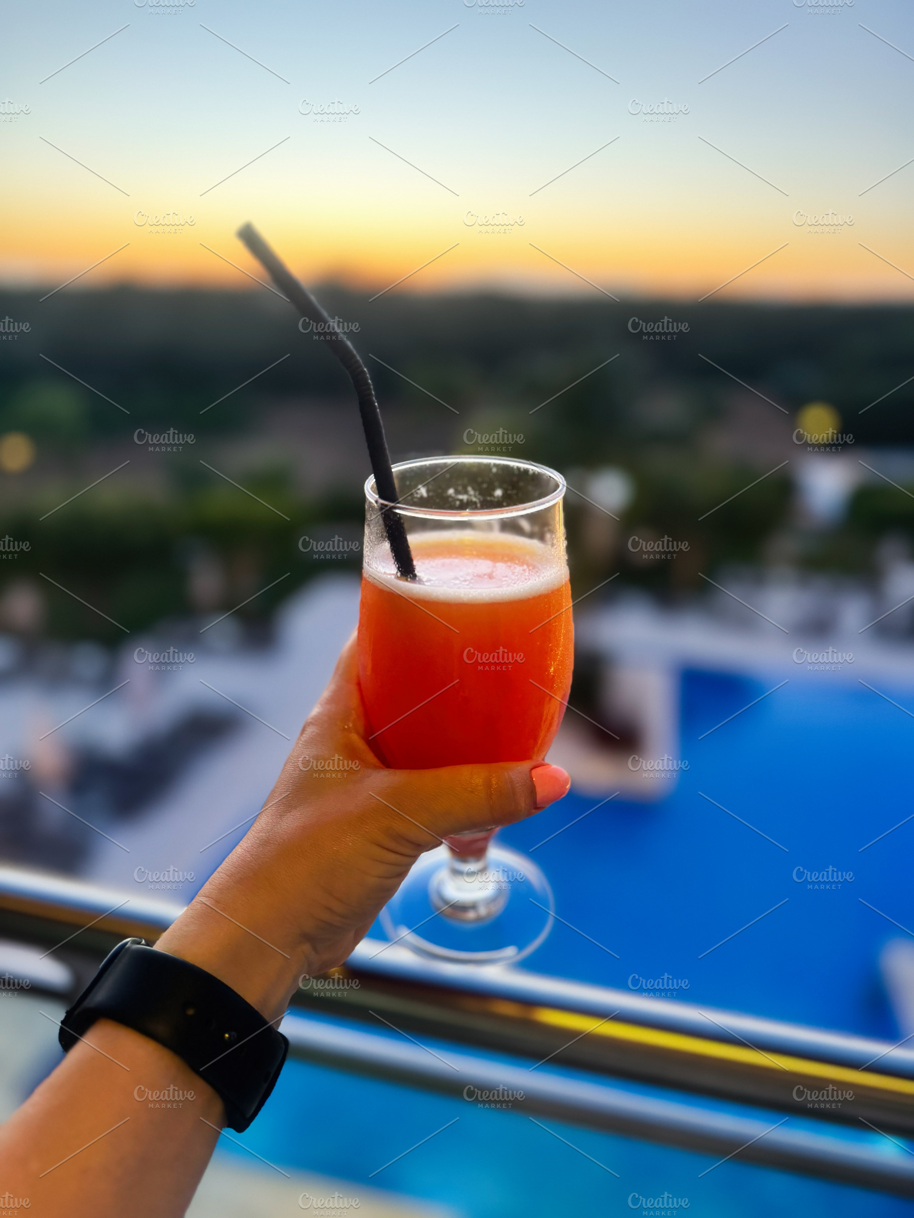 Refreshing cocktail held against scenic sunset view in Algarve, Portugal, a Photo by AS photostudio