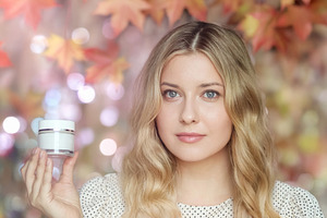 Blonde woman holding face cream, autumn skin care concept with f, a Person Photo by Anneleven