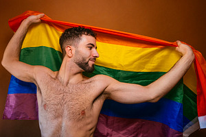 Man holding rainbow pride flag celebrating lgbtq+ identity, a Photo by karrastock