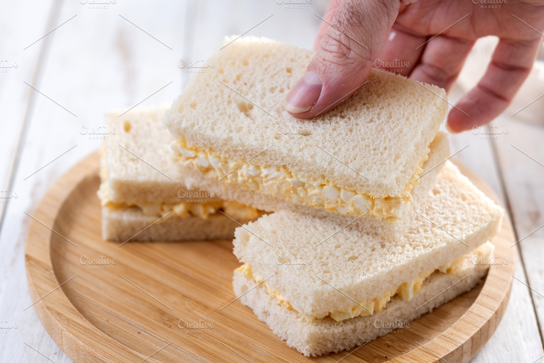 Hand taking a Tamago Sando sandwich, a Photo by etorres69