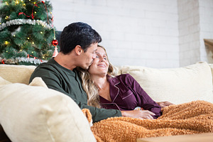 Man kissing woman while relaxing together at Christmas, a Person Photo by etorres69