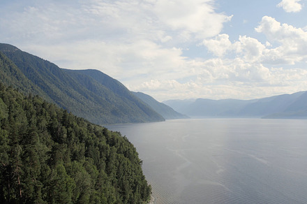 Lake Teletskoye between mountains with blue clear sky in Altai, a Nature Photo by TravelFlow