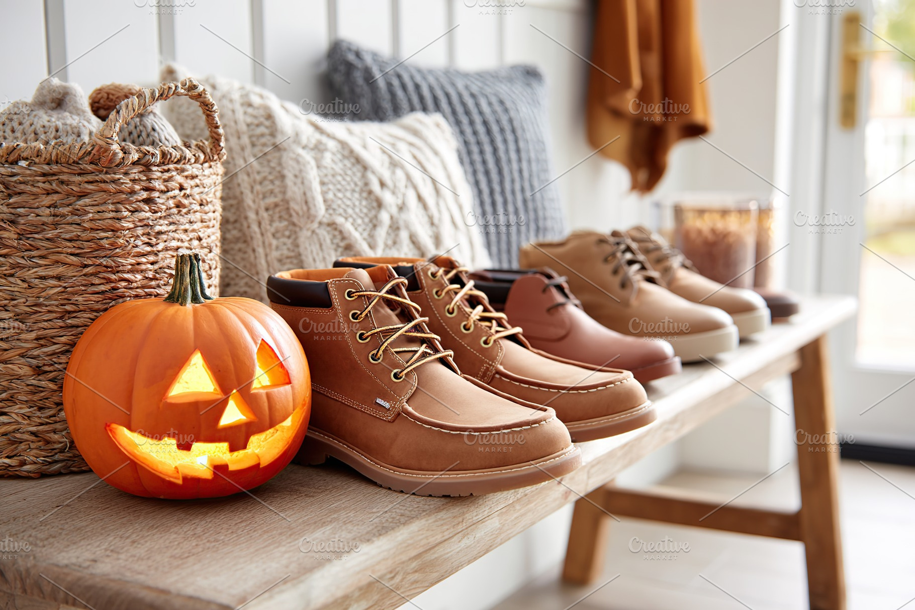 Collection of stylish boots and a carved pumpkin on a rustic bench in autumn, a Holiday Photo by AlyaAnd