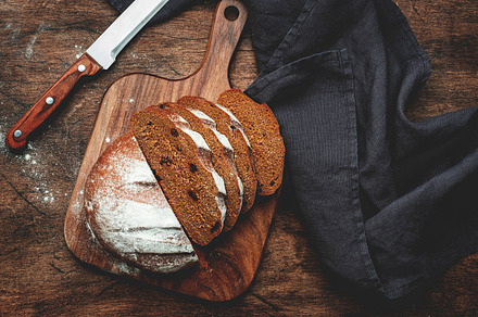 Sourdough rye bread with raisins, pieces on wooden cutting board, a Food & Drink Photo by 5PH