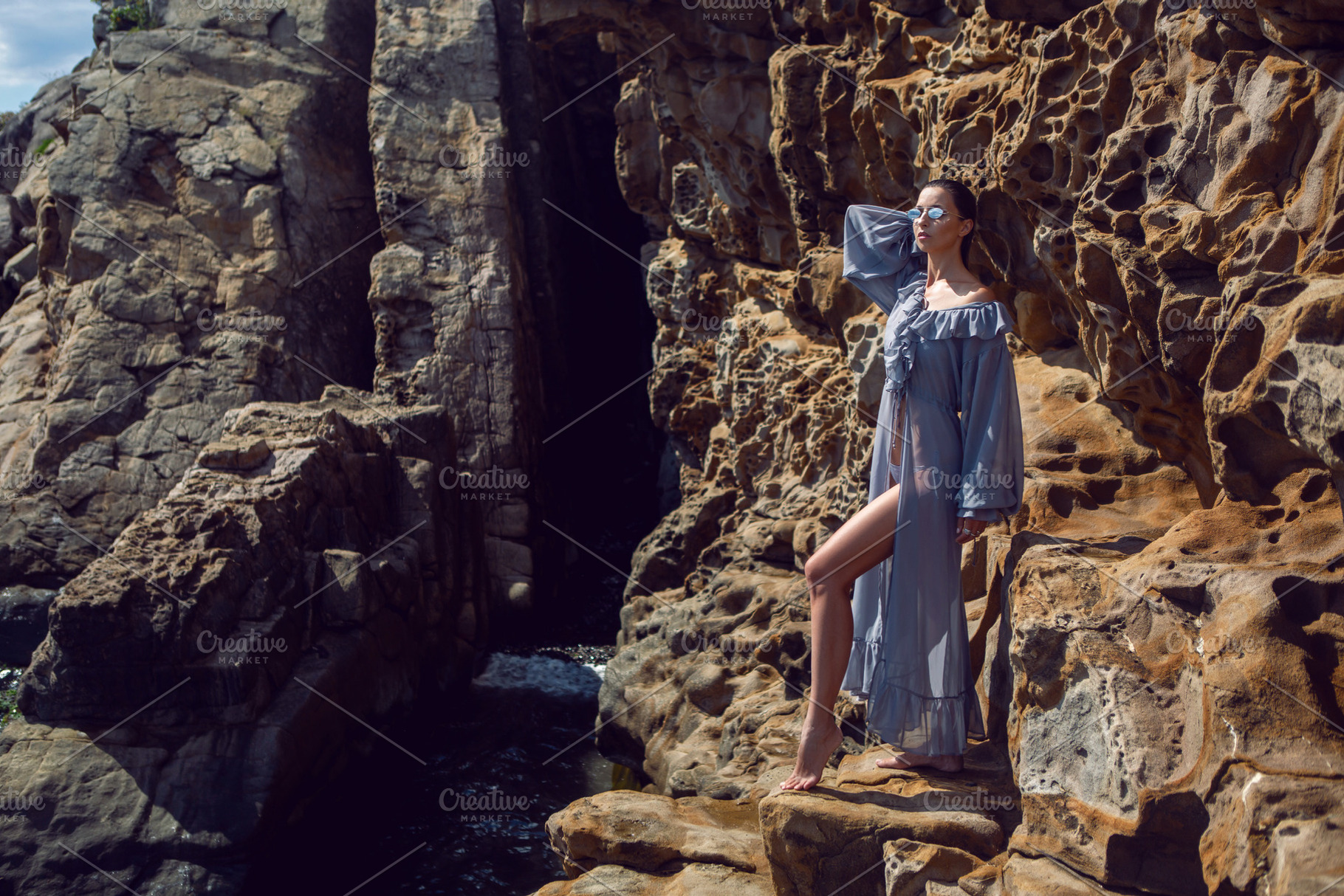 fashionable brunette girl in a gray dress stands on a cheese rock in the summer, a Person Photo by SaulichPhoto