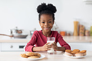 Cheerful Black Girl Sitting At Table, Enjoying Milk And Cookies, a Photo by Prostock-Studio (Thumbnail 1 of 2)