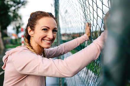 Sportswoman with boxer braids smiling leaning on a metal fence, a Sports & Recreation Photo by davidpereiras