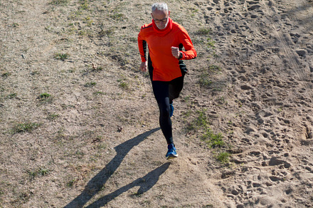 Senior man running on dirt trail from aerial perspective
