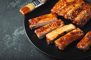 Hot grilled spare ribs from a summer BBQ served on a plate with sauce. Top view, a Food & Drink Photo by Budarinphoto