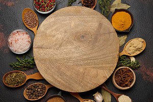 Spices around a round wooden board. Copy space, a Food & Drink Photo by ndanko