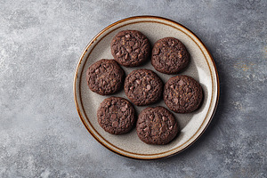 Delicious homemade chocolate cookies arranged neatly on a rustic plate, a Food & Drink Photo by AlyaAnd