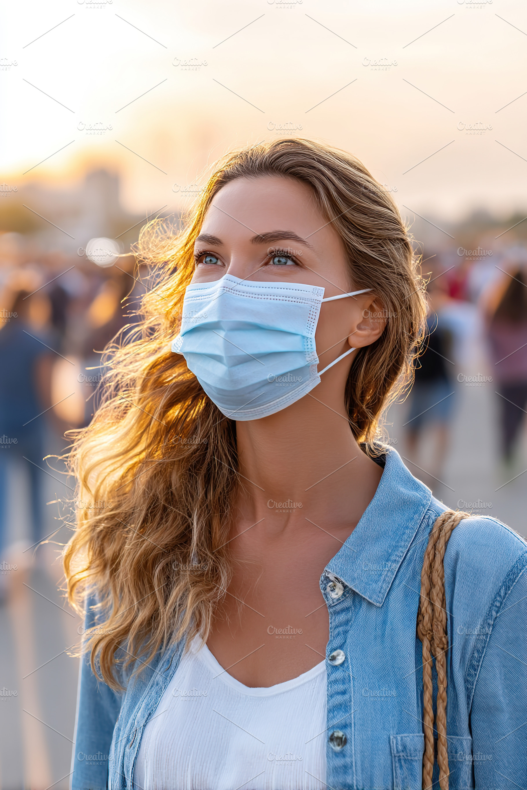 Beautiful woman wearing a mask outdoors at sunset with a crowd in the backdrop, a Person Photo by AlyaAnd