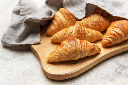 Freshly baked croissants resting on wooden cutting board with li