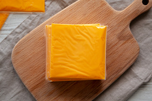 Stack of American Cheese Slices in Wrappers, top view. Flat lay,, a Food & Drink Photo by LiudmylaChuhunova