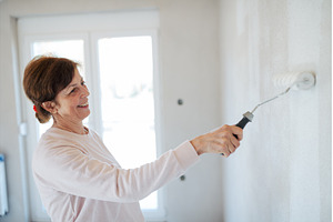Senior woman painting walls with, a Person Photo by HalfPoint