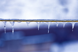 Clear icicles forming on a wire, against a cool blue background., a Background Photo by Ales Munt