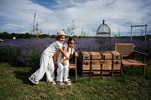 Children playing in a lavender field with wooden chest and chairs, a Photo by AS photostudio