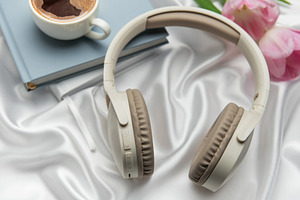 Wireless headphones, coffee, book, and pink tulips resting on wh, a Technology Photo by Olena Rudo