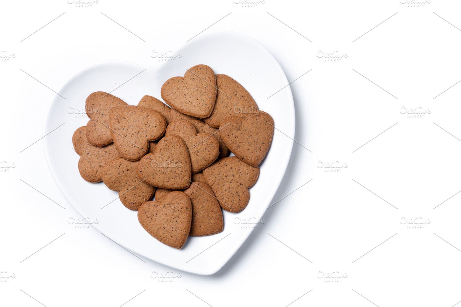 Heart-shaped gingerbread cookies on a white heart-shaped plate isolated on whit, a Food & Drink Photo by etorres69