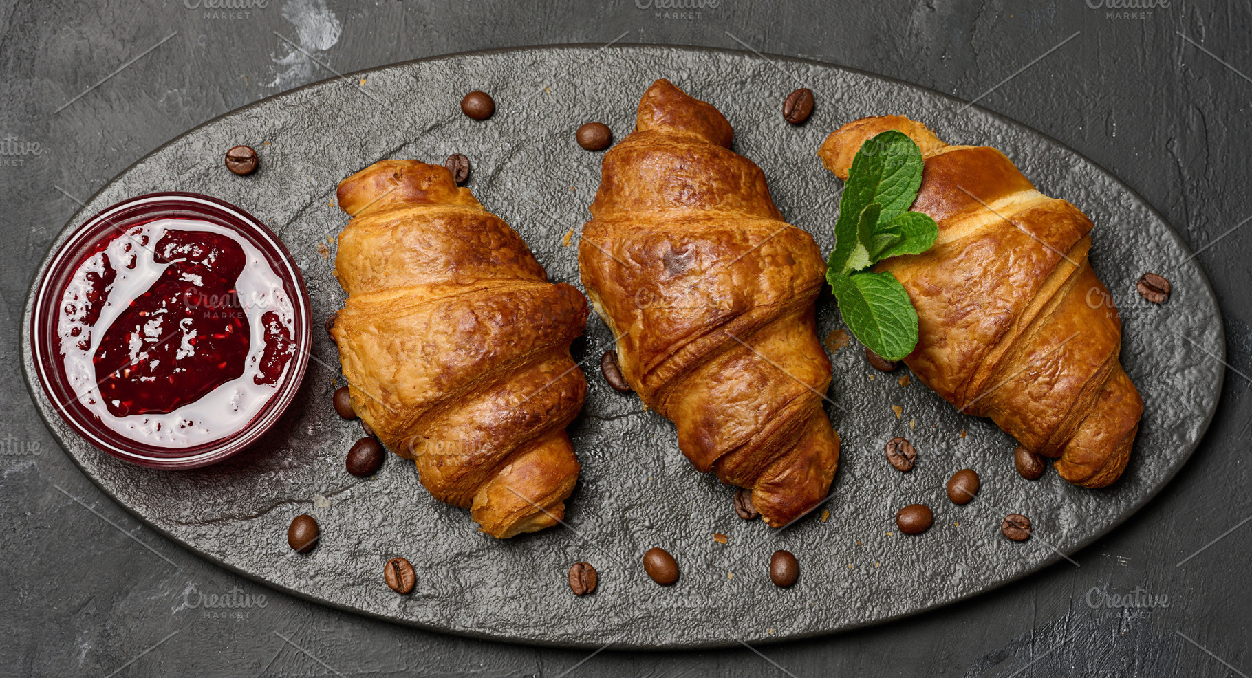 Golden croissants lined up on a dark stone board with raspberry, a Food & Drink Photo by ndanko